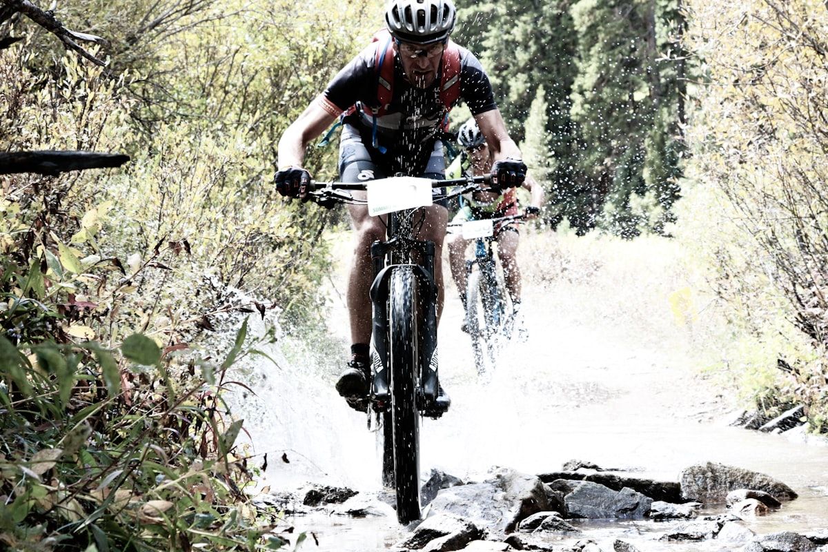 Mountain biker splashing through a stream on a forest trail
